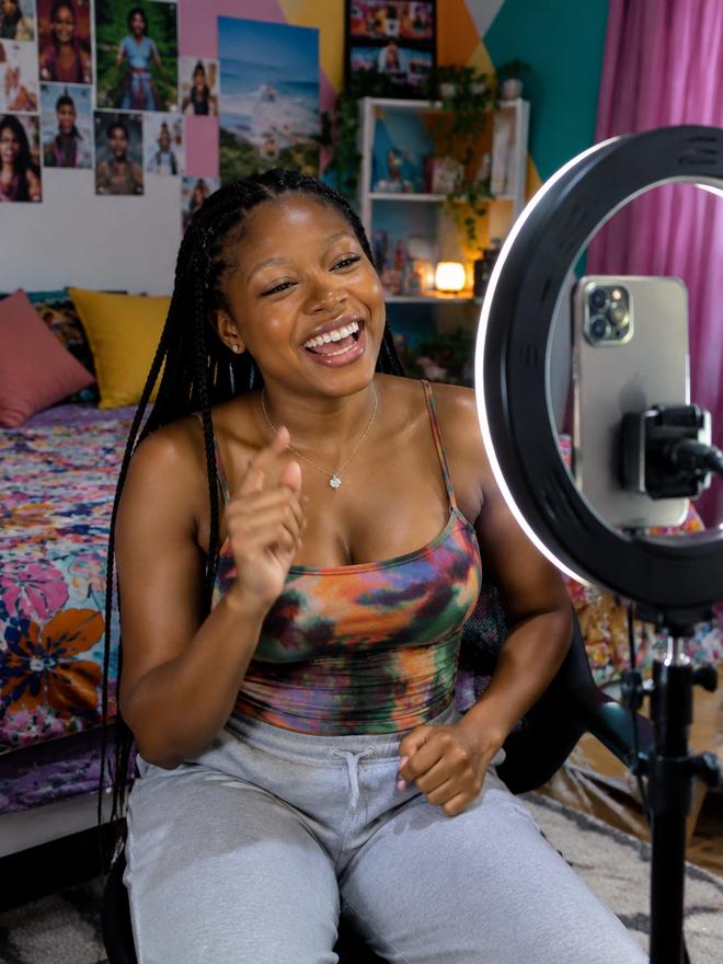 A content creator filming on a phone with a ring light